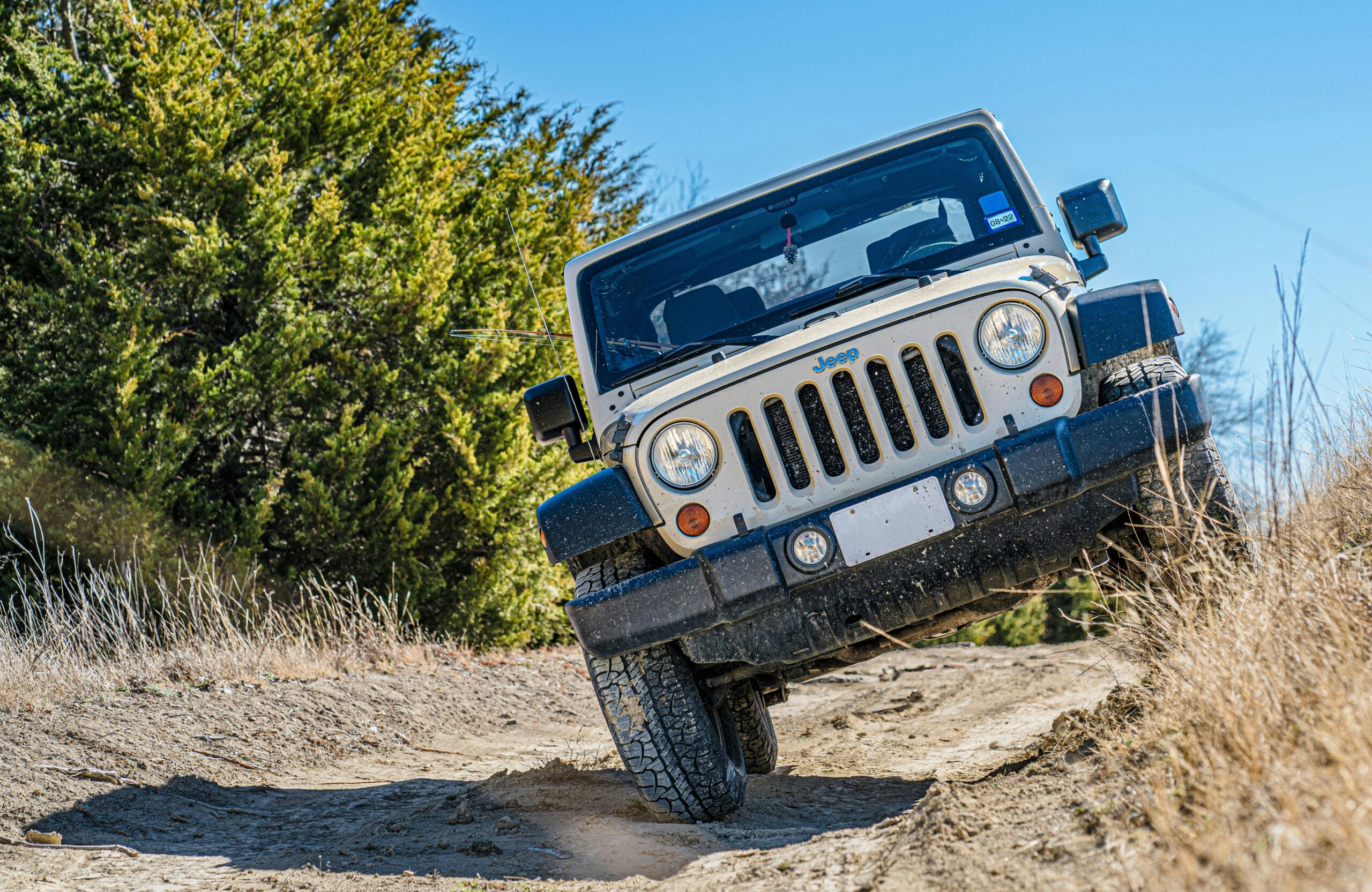 A Jeep navigating a challenging dirt road, showcasing off-road capabilities under a clear sky.