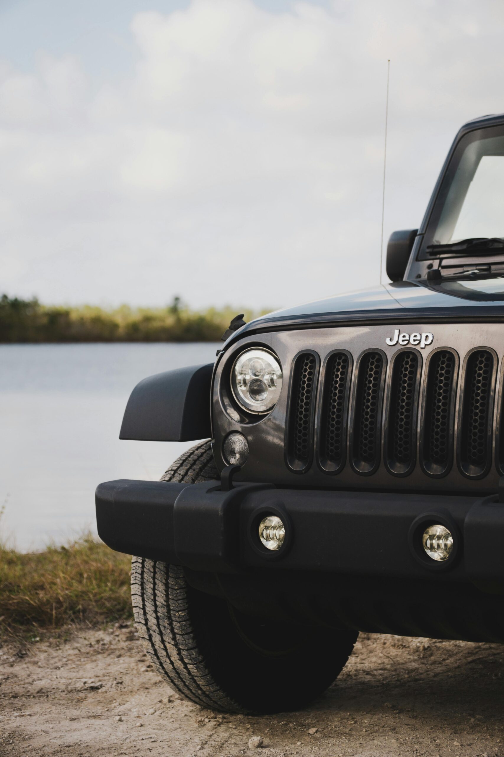 A detailed shot of a black Jeep SUV parked by a serene rural lake in Florida.